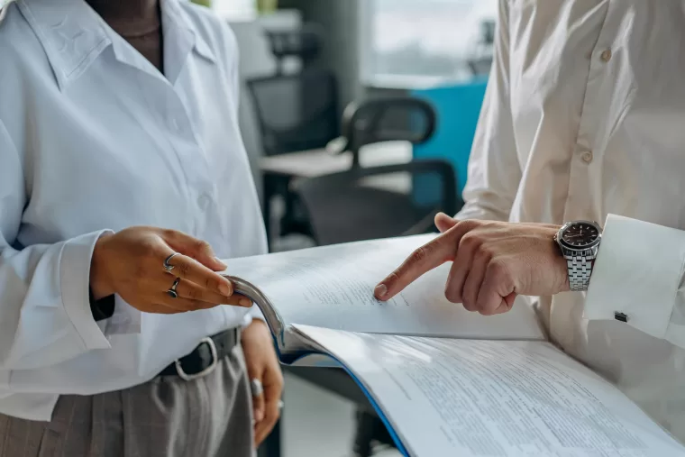 Two people discussing inventory management data on paper.