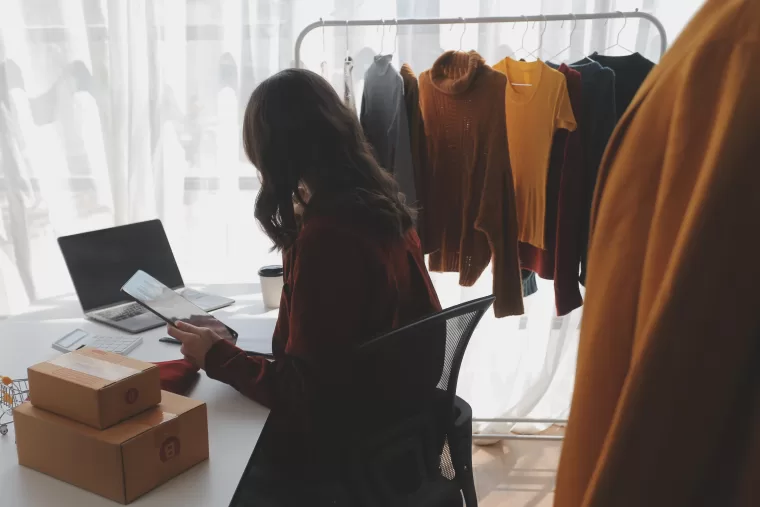 Woman organising inventory on her laptop for her fashion business.