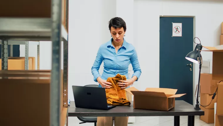 Woman folding clothes in a warehouse.